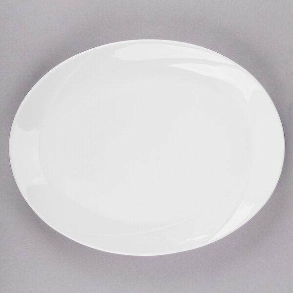 A Tuxton San Marino AlumaTux Pearl White oval platter with a white rim on a gray surface.