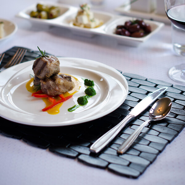 A Tuxton AlumaTux Pearl White china plate with food on a table.