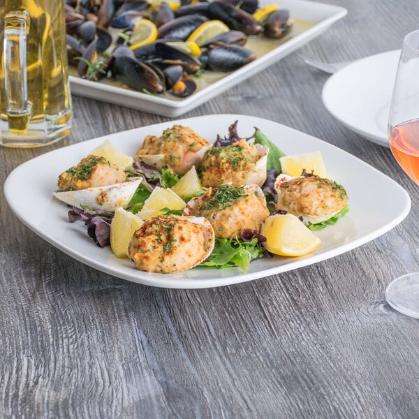 A Tuxton AlumaTux square china plate with mussels and a lemon wedge.
