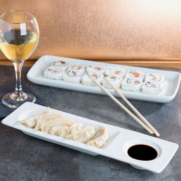 A Tuxton rectangular white china plate with sushi and chopsticks on it.