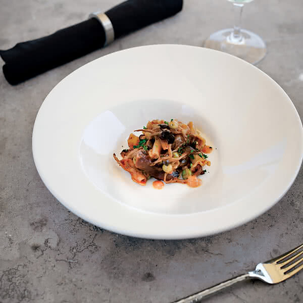 A Tuxton AlumaTux Pearl White china bowl on a table with food.