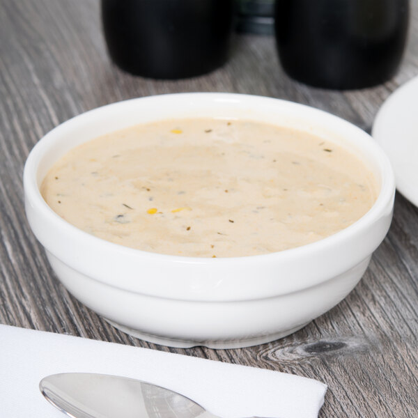 A Tuxton AlumaTux pearl white china bowl filled with soup on a table.