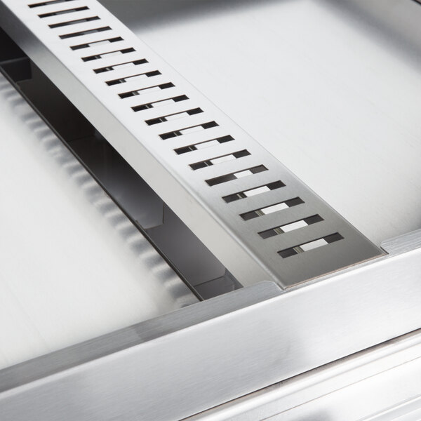 A close-up of a copper Hatco countertop with drains.