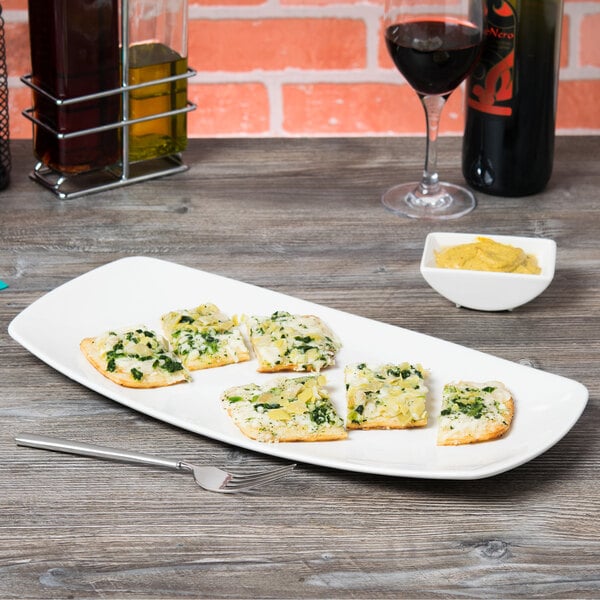 A Tuxton rectangular white china plate with food and a glass of wine on a table.