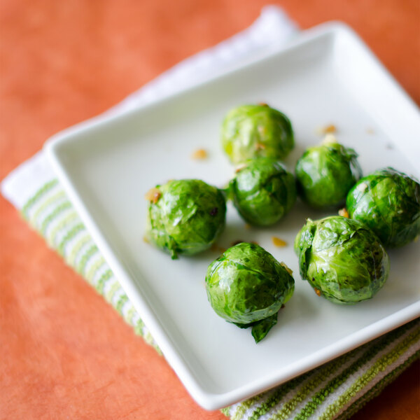 A Tuxton AlumaTux Pearl White square china plate with brussels sprouts.