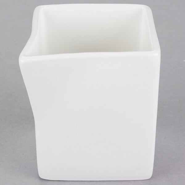 A Tuxton Pearl White ceramic creamer with a curved bottom.