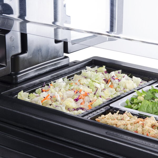 A black melamine food pan filled with salad on a counter.