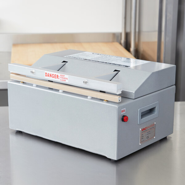 A grey rectangular ARY VacMaster seal bar tape machine sitting on a counter.