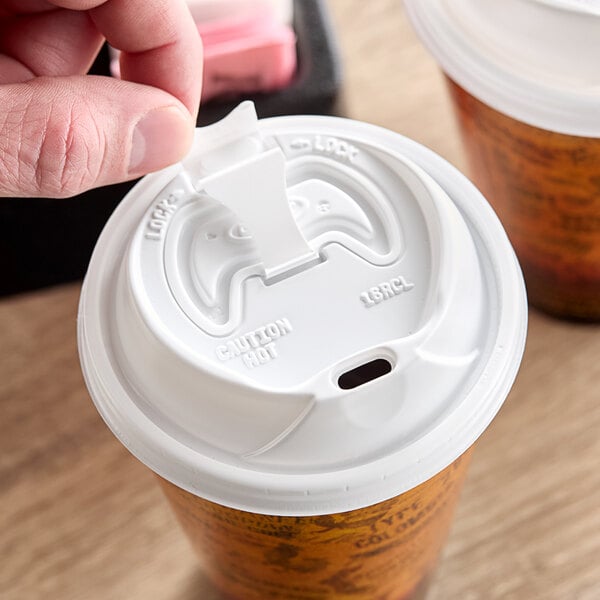 A person's hand using a Dart white travel lid on a coffee cup.