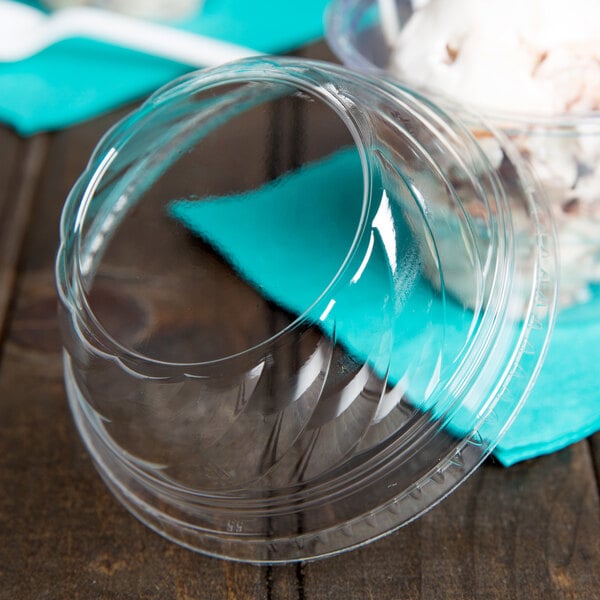 A close-up of a Fabri-Kal clear plastic dome lid on a clear plastic container of ice cream.