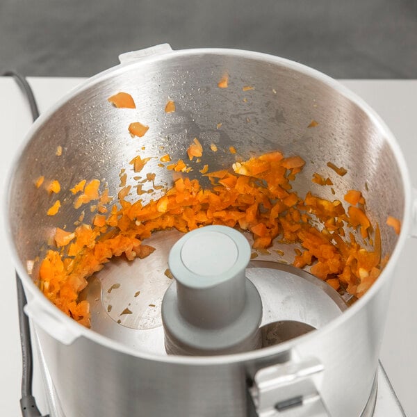 A Robot Coupe food processor with carrots in it.