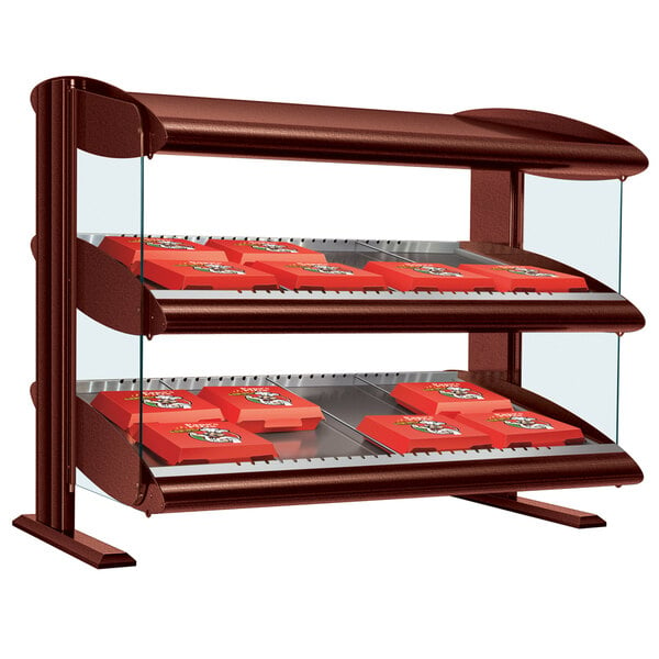 An Antique Copper Hatco countertop display case with slanted double shelves holding red boxes.