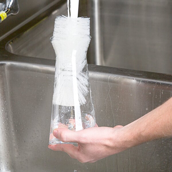 A person using a Carlisle bottle brush to clean a glass.