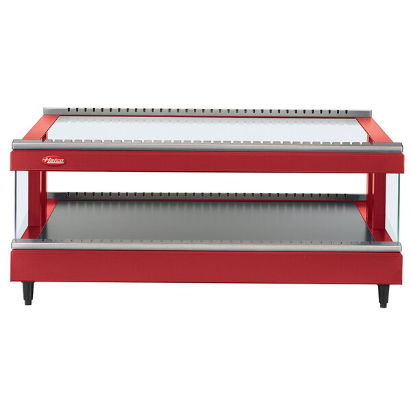 A red and silver rectangular Hatco heated glass display shelf on a table in a bakery.