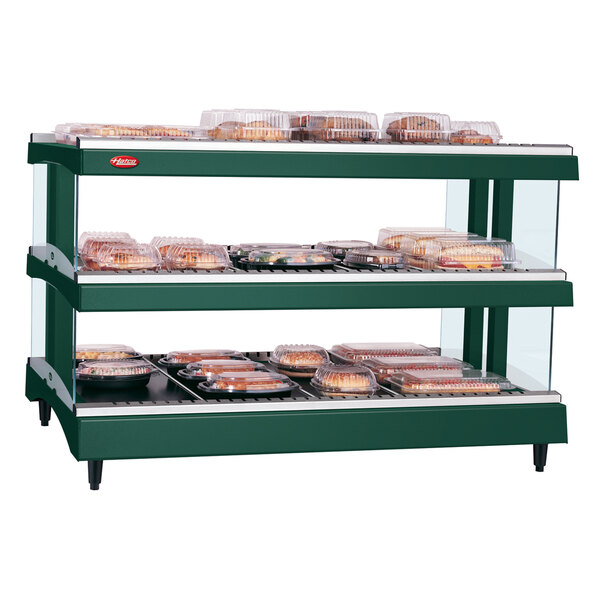 A Hunter Green Hatco heated glass food display case with trays of food on a shelf.