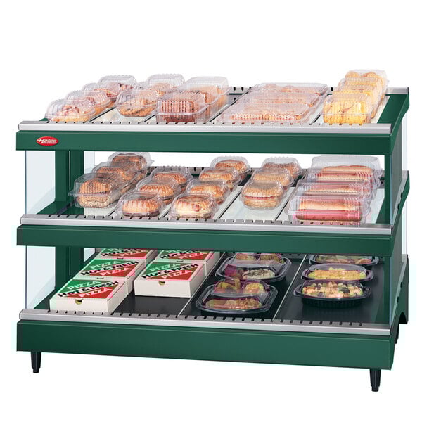 A Hunter Green Hatco Glo-Ray food display case with trays of food on a slanted double shelf.