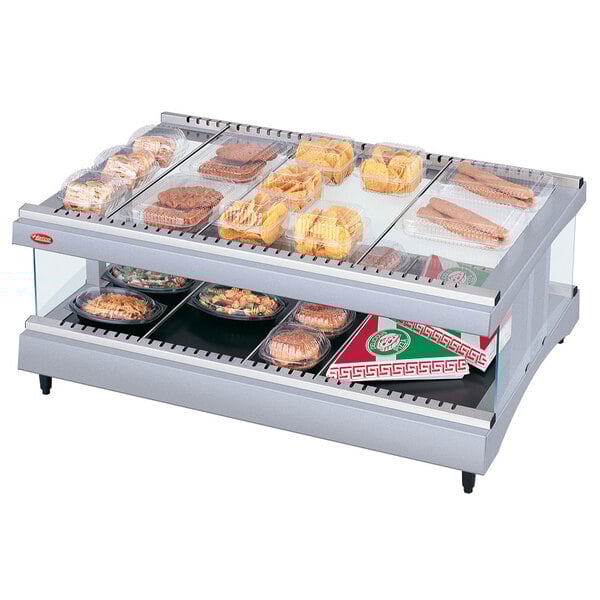 A Hatco heated glass display case with trays of food on top.