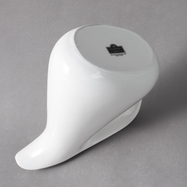 A white porcelain milk jug with a logo on it.