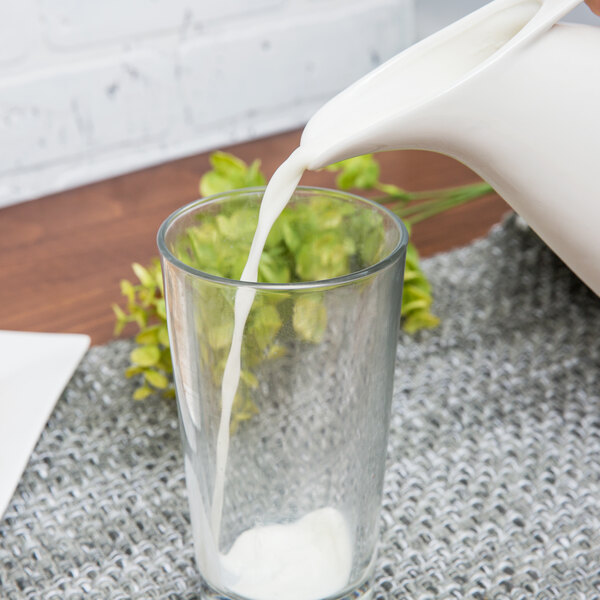 A Whittier porcelain milk jug pouring milk into a glass.