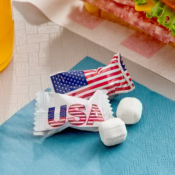 A pair of individually wrapped buttermints with American flag-themed packaging placed on a blue napkin.