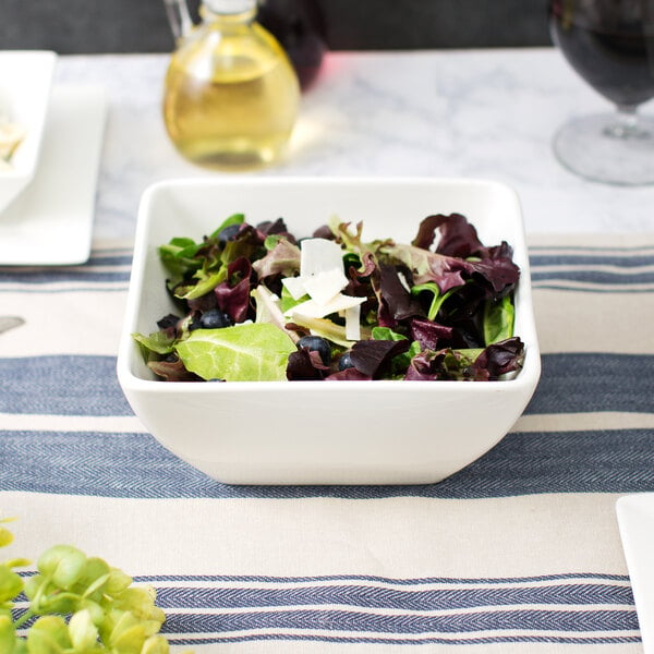 A bowl of salad with blueberries and cheese in a white bowl.