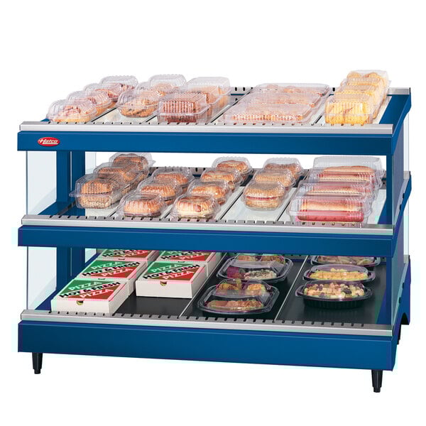 A navy blue Hatco heated glass merchandising warmer with shelves of food on a counter.