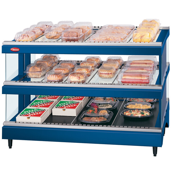A navy blue Hatco food warmer with heated shelves holding food on a bakery counter.
