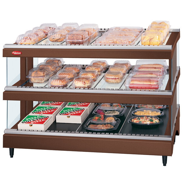 A Hatco countertop heated glass merchandising warmer with food on shelves.