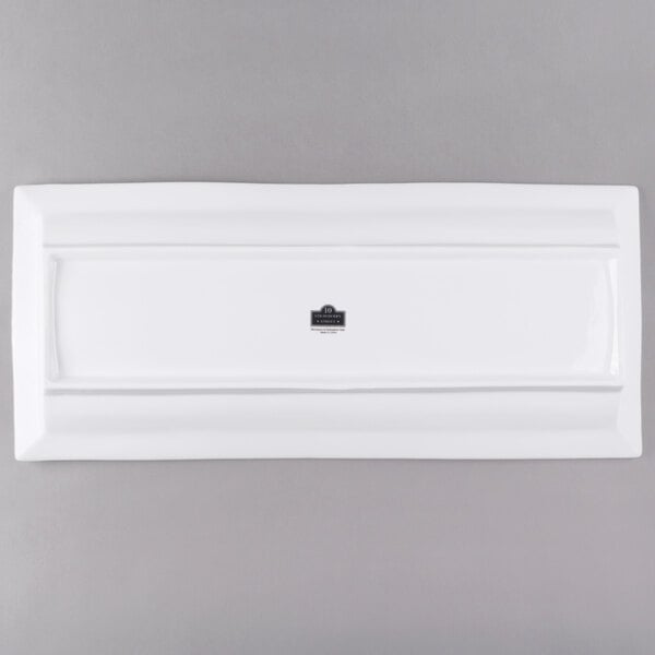 A white rectangular plate with a ridged edge and a black logo on the bottom.