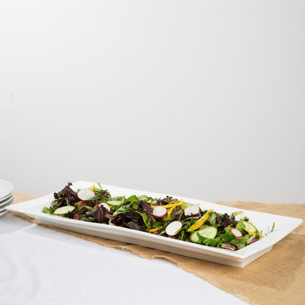 A 10 Strawberry Street white porcelain ridge platter with a plate of salad on a table.