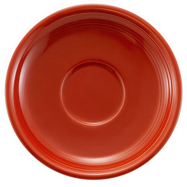 A red round saucer with a circular object in the middle.