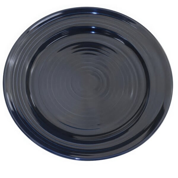 A cobalt blue round plate with a spiral pattern.