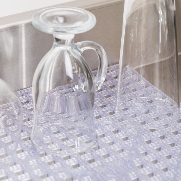 Clear San Jamar Versa-Mat under a glass pitcher on a counter.