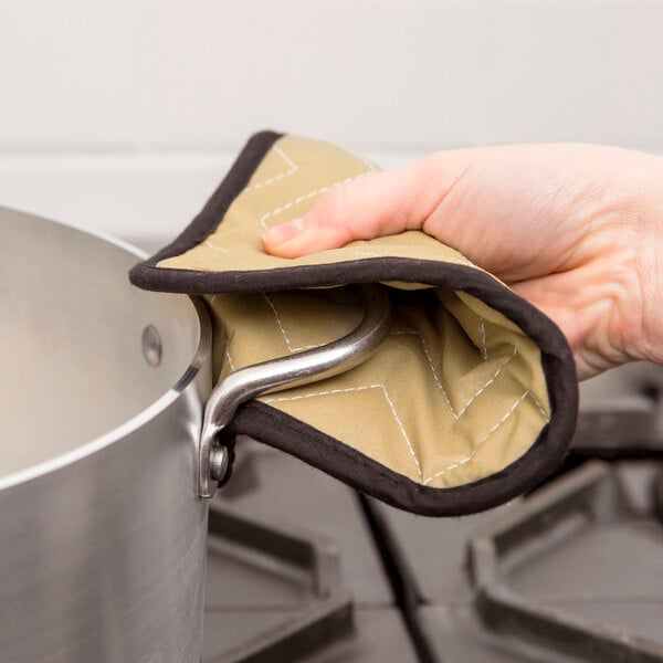 A hand using a San Jamar Bestan cotton pot holder to hold a pot.