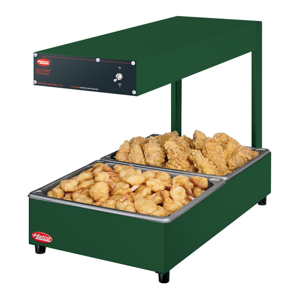 A green Hatco food warmer with chicken and fries on a tray.