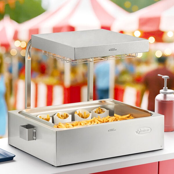A Hatco fry holding station with french fries inside on a counter in an outdoor catering setup.