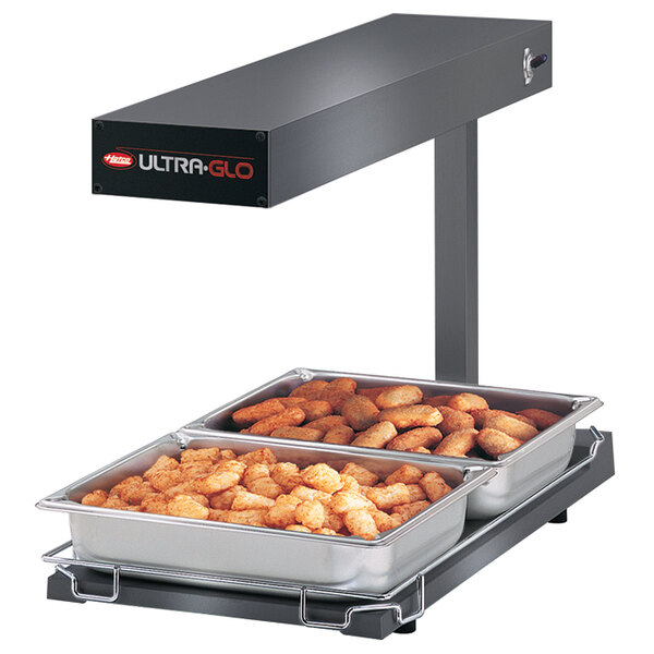 A Hatco portable food warmer with trays of tater tots on a heated shelf.