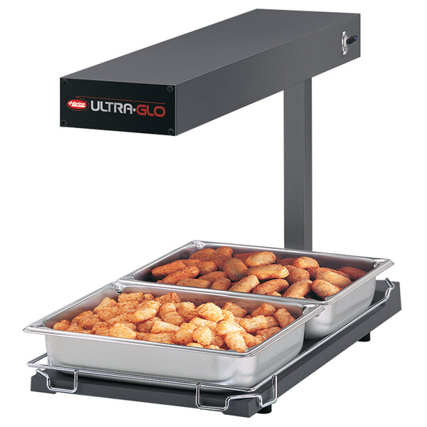 A Hatco Ultra-Glo food warmer with two trays of food on a counter.