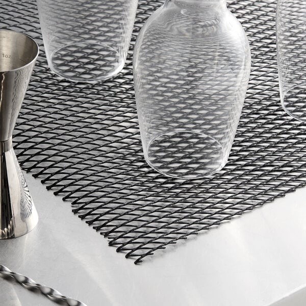A group of glasses on a black San Jamar shelf liner.