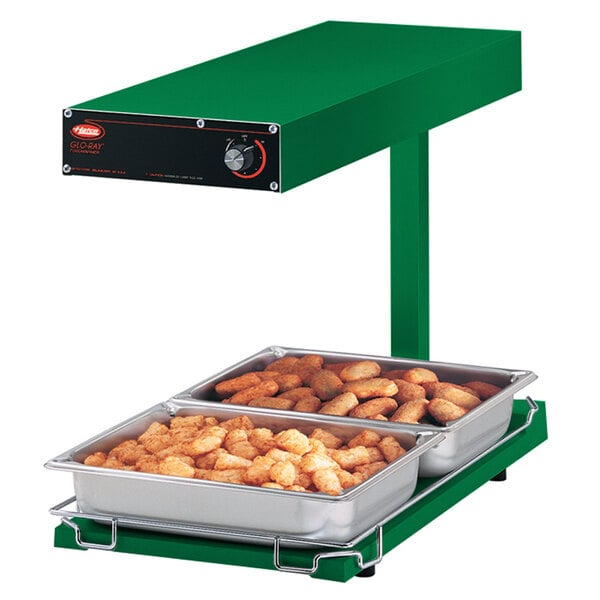 A Hatco green portable food warmer with trays of tater tots inside.