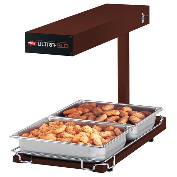 A Hatco Ultra-Glo food warmer with trays of tater tots on a counter.