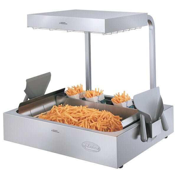 A Hatco fry holding station with french fries in a container on a metal counter.