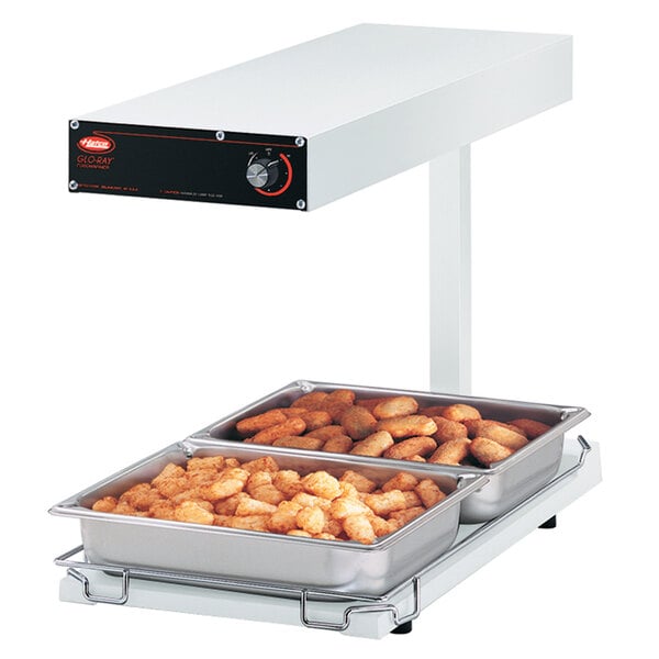 A Hatco heated shelf with trays of food on it.
