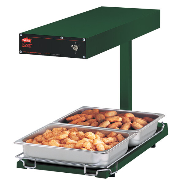 A Hatco Glo-Ray food warmer with tater tots and trays of food on a counter.