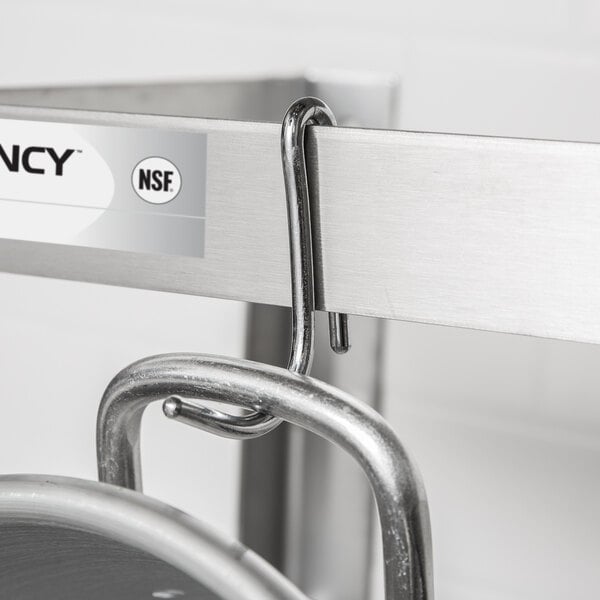 A metal hook is hanging from a stainless steel bar, holding a pot by its handle.