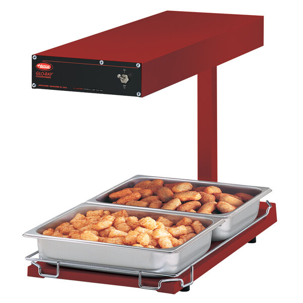 A red Hatco food warmer with trays of food on a heated shelf.