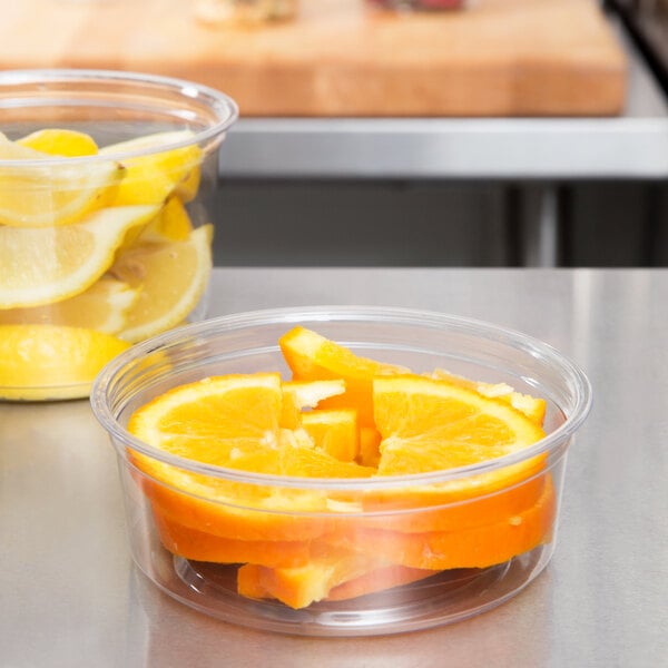 A Fabri-Kal deli container filled with sliced oranges and lemons.