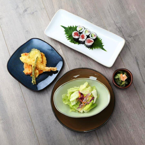 A Tuxton Artisan Mojave China plate with sushi on a table.