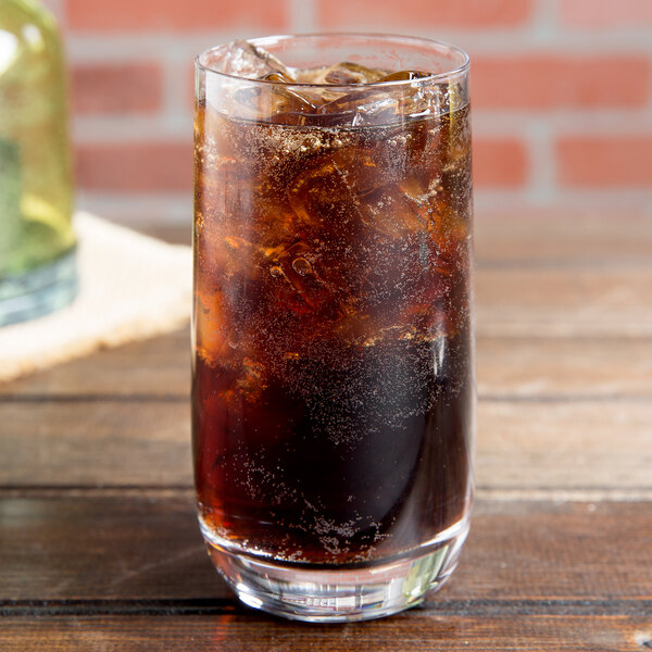 A Stolzle Weinland tumbler filled with soda and ice on a table.