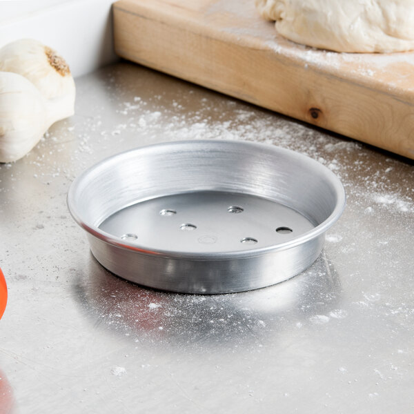 An American Metalcraft silver aluminum pizza pan on a counter.